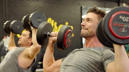 man doing shoulder press in gym